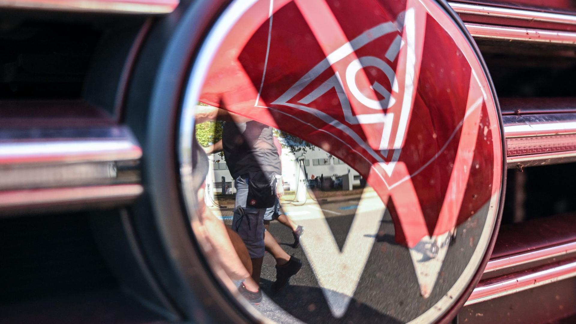 Eine Fahne der IG Metall spiegelt sich in einem VW Logo. | dpa-Bildfunk / Hendrik Schmidt