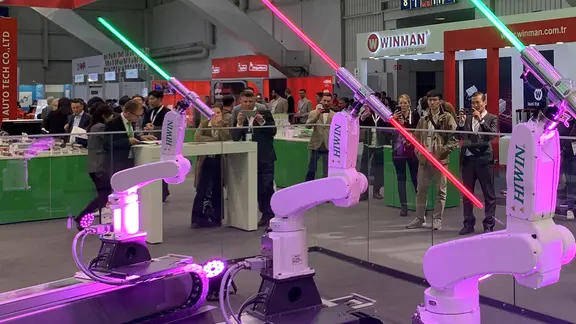 Besucher der Hannover Messe schauen sich an einem Messestand Roboter an.