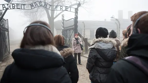 Auschwitz-Guide Halina Swiderska bei einer Führung unter dem Tor mit der Aufschrift "Arbeit macht frei"