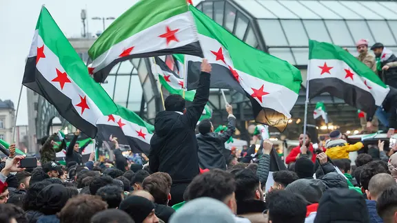 Zahlreiche Menschen feiern am Hachmannplatz am Hauptbahnhof den Sturz von Syriens Machthaber Assad.