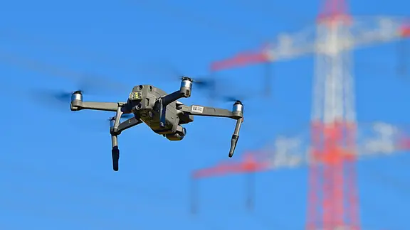 Eine Drohne fliegt in der Nähe einer Stromleitung.
