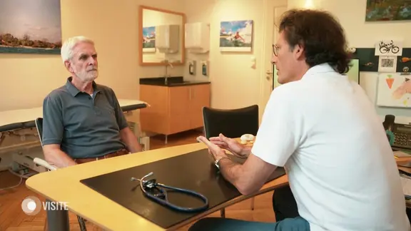 Arzt und Patient sitzen sich gegenüber und sprechen miteinander.