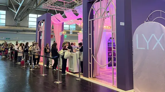 Eine Schlange vor einem rosa beleuchteten Pavillon auf einer Buchmesse