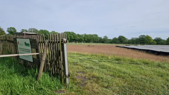 Auf einem Feld stehen mehrere weiße Antennen und daneben ist etwas viereckiges mit einer schwarzen Plane abgedeckt.