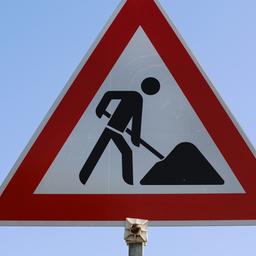 Ein Verkehrsschild vor klarem Himmel weist auf eine Baustelle hin