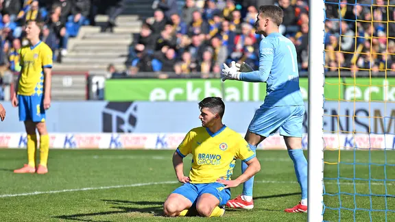 Jannis Nikolaou (M.) von Eintracht Braunschweig sitzt nach seinem Eigentor gegen Hertha BSC frustriert auf dem Rasen