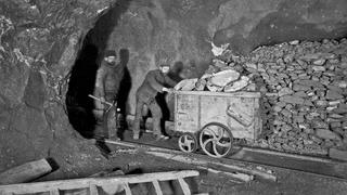 Bergarbeiter mit einem Förderwagen beim Erztransport in einem Stollen um 1910