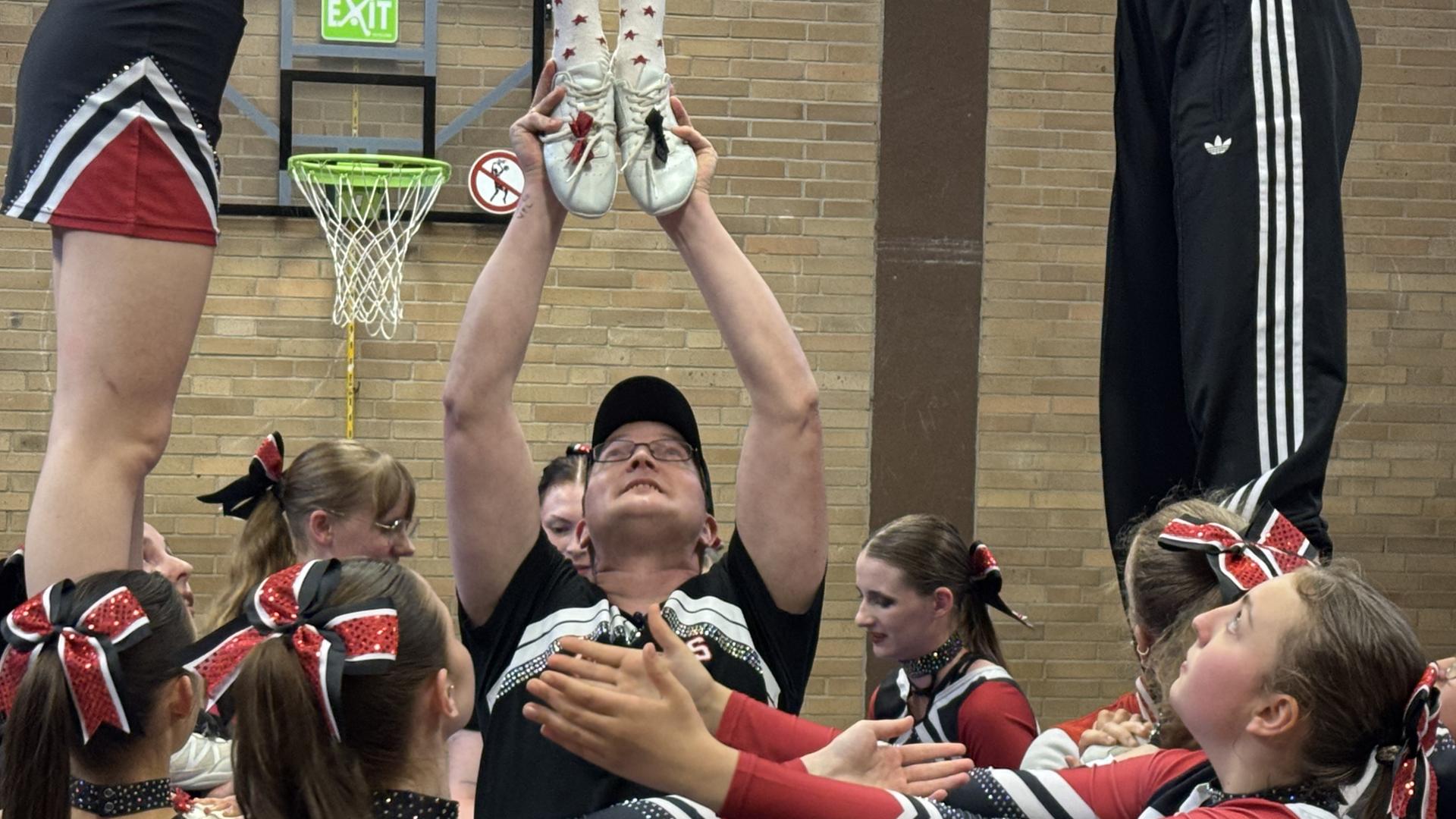 Ein Mann stemmt ein Mädchen hoch. Um ihn herum stehen viele Cheerleader. | NDR, Anita Westrup
