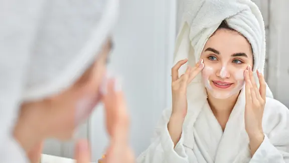 Frau mit Handtuch über den Haaren cremt sich das Gesicht ein. | colourbox.de Frau mit Handtuch über den Haaren cremt sich das Gesicht ein.