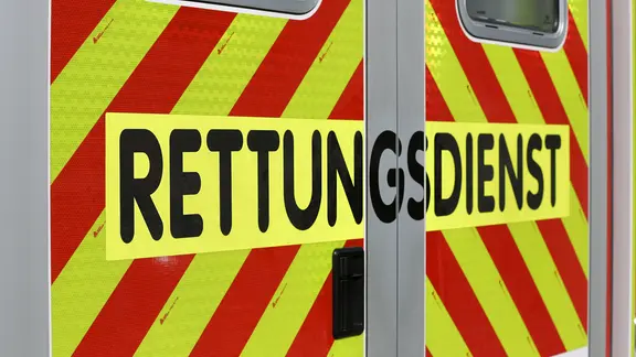 Schriftzug "Rettungsdienst" steht auf einem gelb-rot gestreiften Einsatzfahrzeug.