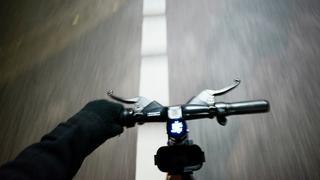 Aus der POV ist eine Person zu sehen, die einhändig E-Scooter auf einer Straße fährt.