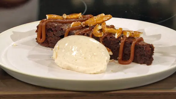 Brezel-Schokokuchen mit Erdnussbuttercreme und Karamellsoße auf einem Teller serviert | NDR Brezel-Schokokuchen mit Erdnussbuttercreme und Karamellsoße auf einem Teller serviert