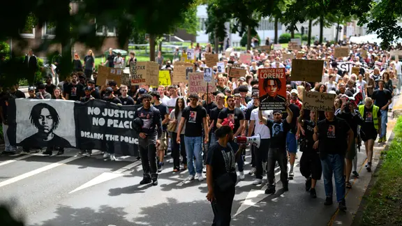 Teilnehmer einer Demonstration «Gerechtigkeit für Lorenz» gehen hinter einem Transparent mit einem Bildnis und mit dem Aufdruck «No Justice, No Peace! Disarm The Police».