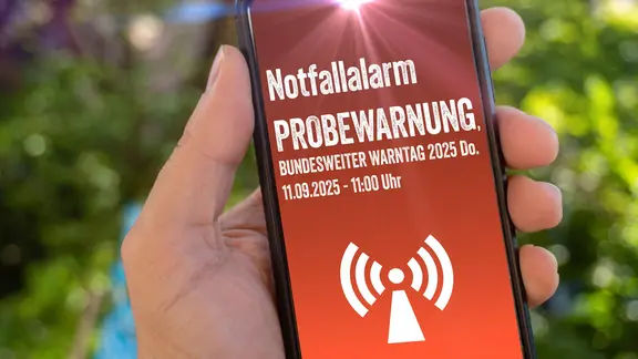 Fotomontage: Text auf einem Handy weist auf den Warntag am 11. September hin