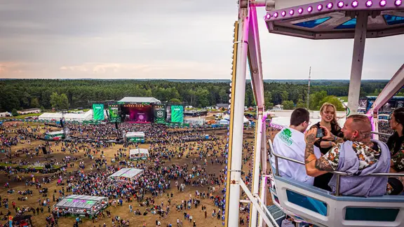 Blick aus der Gondel eines Riesenrads auf Besucher des Hurricane Festivals und das Festivalgelände.