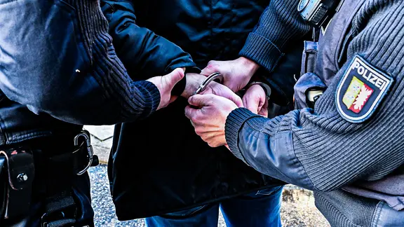 Die Hände von Polizisten legen Handschellen an die Hände eines Verdächtigen