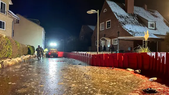 Rote Schutzwände sollen die Häuser in Schleswig vor dem Hochwasser schützen. | Moritz Mayer In Schleswig steht eine Hochwasserschutzwand vor einem Haus.