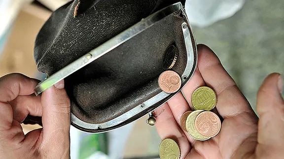 Eine Frau nimmt ein paar Münzen aus einer zerrissenen Geldbörse in die Hand. | picture-alliance/ ZB, Hans Wiedl Eine Frau nimmt ein paar Münzen aus einer zerrissenen Geldbörse in die Hand.