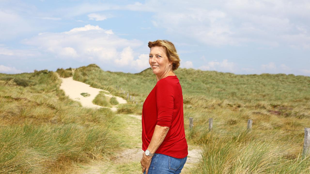 Die Autorin Dora Heldt steht in einer Dünenlandschaft.