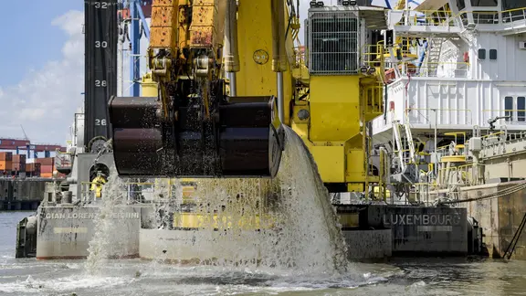 Ein Bagger holt bei Arbeiten zur Elbverteifung Schlick aus einem Hafenbecken.