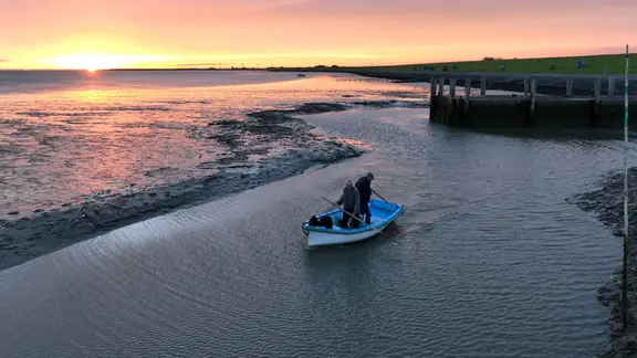 Früh morgens bei Niedrigwasser gelangen die Gebrüder Hellmann nur mit dem kleinen Beiboot zu ihrem Passagierschiff, mit dem sie Exkursionen ins Watt unternehmen.