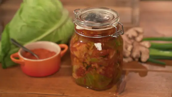 Ein Einmachglas mit Kimchi auf einem Tisch arrangiert.