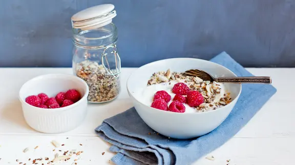 Auf einem Tisch steht ein Schälchen mit Himbeeren, ein Glasbehälter mit Basismüsli und eine kleine Schale mit Löffel, in der beide Zutaten mit Milch gemischt sind. | NDR, Claudia Timmann Auf einem Tisch steht ein Schälchen mit Himbeeren, ein Glasbehälter mit Basismüsli und eine kleine Schale mit Löffel, in der beide Zutaten mit Milch gemischt sind.