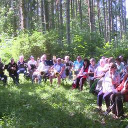 Ein Priester hält eine Andacht im Wald vor Besuchenden.