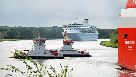 Die Fähren in Nobiskrug queren den Nord-Ostsee-Kanal zwischen zwei großen Schiffen.