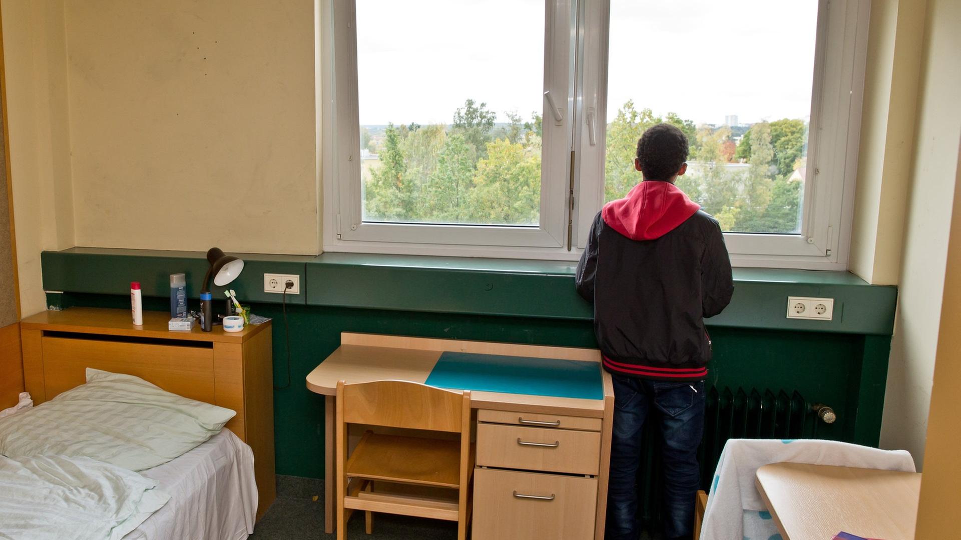 Ein geflüchteter Junge steht an einem Fenster in einer Unterkunft. | picture alliance / dpa, Daniel Karmann