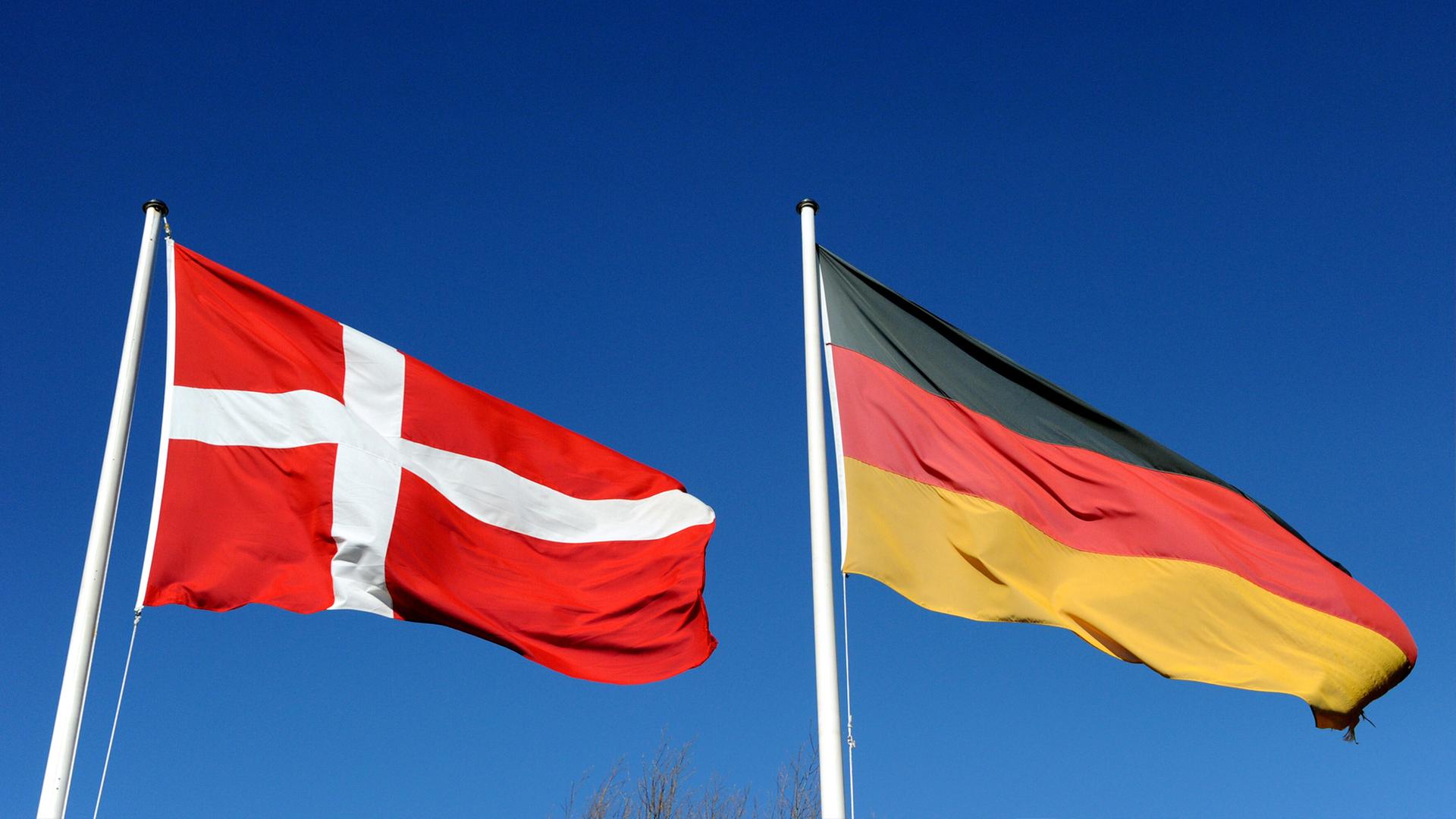 Die deutsche und die dänische Flagge wehen vor blauem Himmel. | dpa, Carsten Rehder
