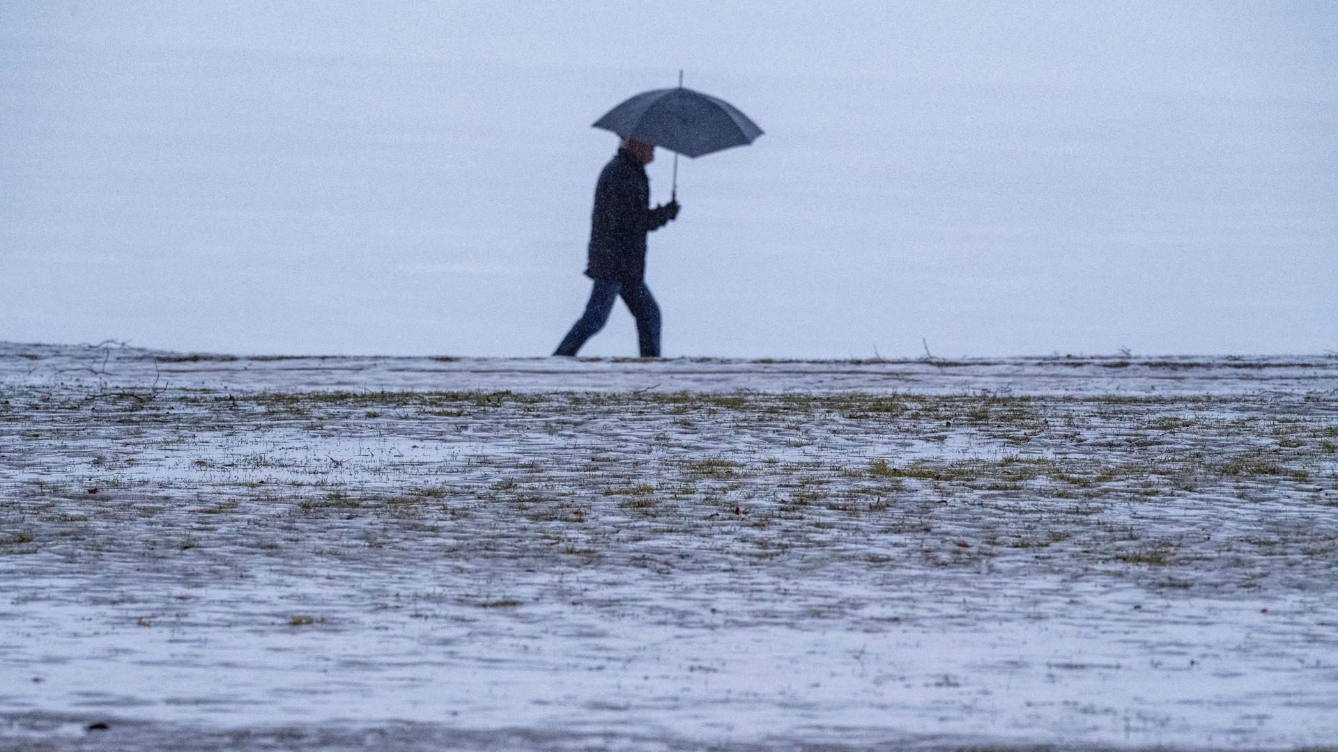 Ein Mann geht mit Schirm durch den Regen. | picture alliance/dpa | Stefan Sauer