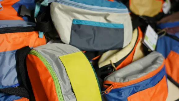 Bauchtaschen aus kaputten Festivalzelten liegen auf einem Haufen.