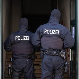 Polizisten stehen während einer Razzia in einer Haustür. (Symbolbild)