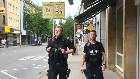 Zwei Polizisten laufen die Straße entlang.