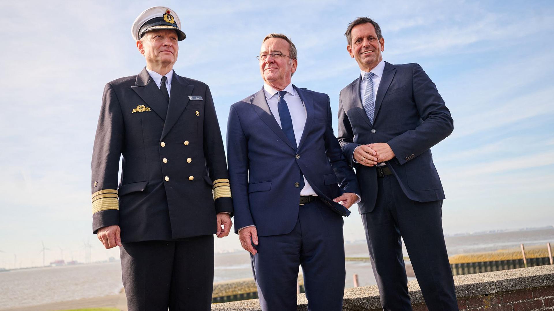 Niedersachsens Ministerpräsident Olaf Lies steht mit Verteidigungsminister Boris Pistorius und Vizeadmiral Wilhelm Tobias Abry in Emden am Deich.  | Sina Schuldt/dpa +++ dpa-Bildfunk +++