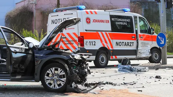Ein schwarzes Unfallauto steht vor einem beschädigten Notarztfahrzeug.