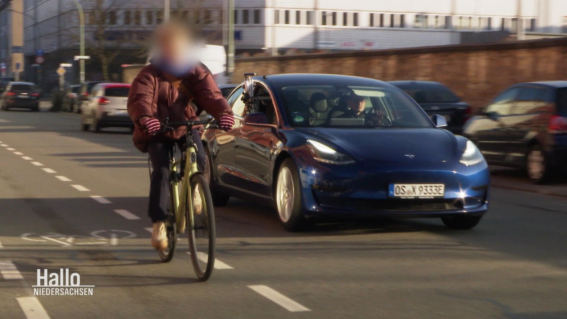 Radfahrerin und Auto mit Messsenoren und Kamera fahren aneinander vorbei. | Screenshot