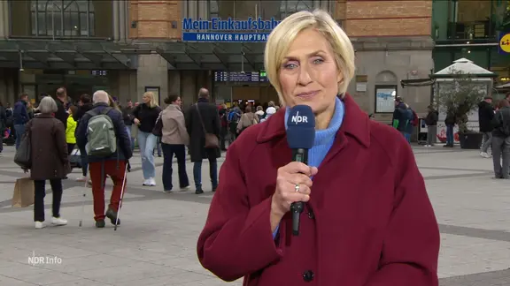 Moderatorin Susanne Stichler steht mit einem Mikrofon vor dem Hauptbahnhof in Hannover.