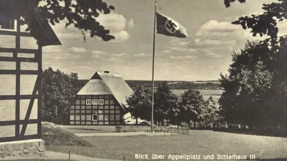 Eine historische Ansichtskarte von Alt Rehse. Auf einem Appellplatz steht ein Fahnenmast mit einer Hakenkreuzfahne.