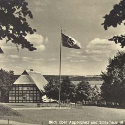 Eine historische Ansichtskarte von Alt Rehse. Auf einem Appellplatz steht ein Fahnenmast mit einer Hakenkreuzfahne.