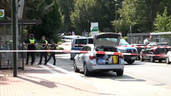 Eine Polizistin und ein weiße Schutzanzüge gekleidete Einsatzkräfte sichern Spuren am Tatort in Sarstedt.