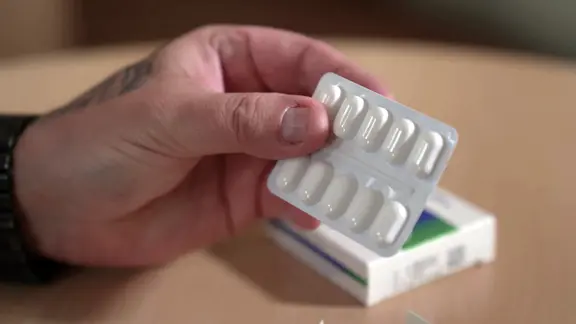 Patient Daniel S. hält ein Blister Schmerztabletten in der Hand.
