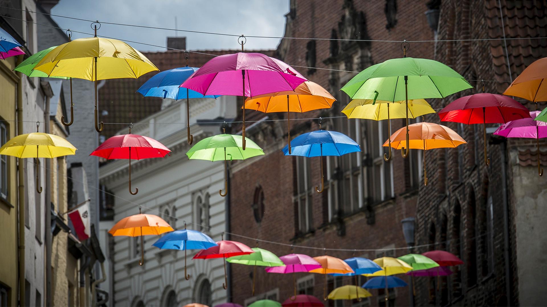 Schirme hängen über einer Straße zwischen altern Häusern. | Lübeck und Travemünde Marketing GmbH