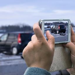 Eine Frau fotografiert mit ihrem Smartphone einen Unfall (Montage)