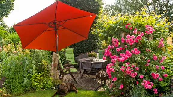 Sitzecke mit Sonnenschirm in einem Garten. 