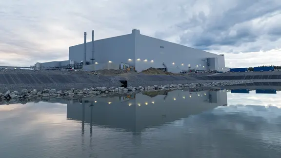 Eine Fabrikhalle steht in der Nähe einer Wasserfläche.