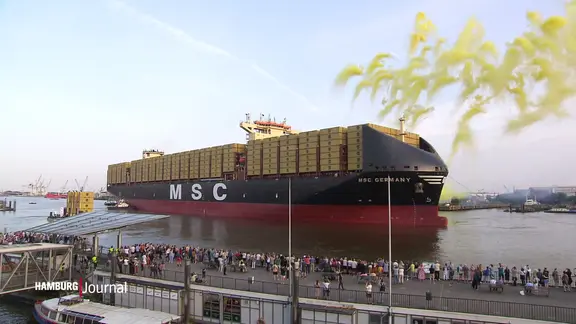 Ein Containerschiff liegt vor den Hamburger Landungsbrücken im Hafen.