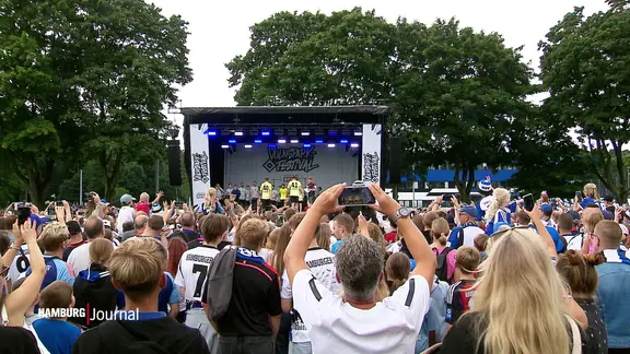 Blick über eine Menge von HSV-Fans, die vor einer aufgebauten Bühne feiern.