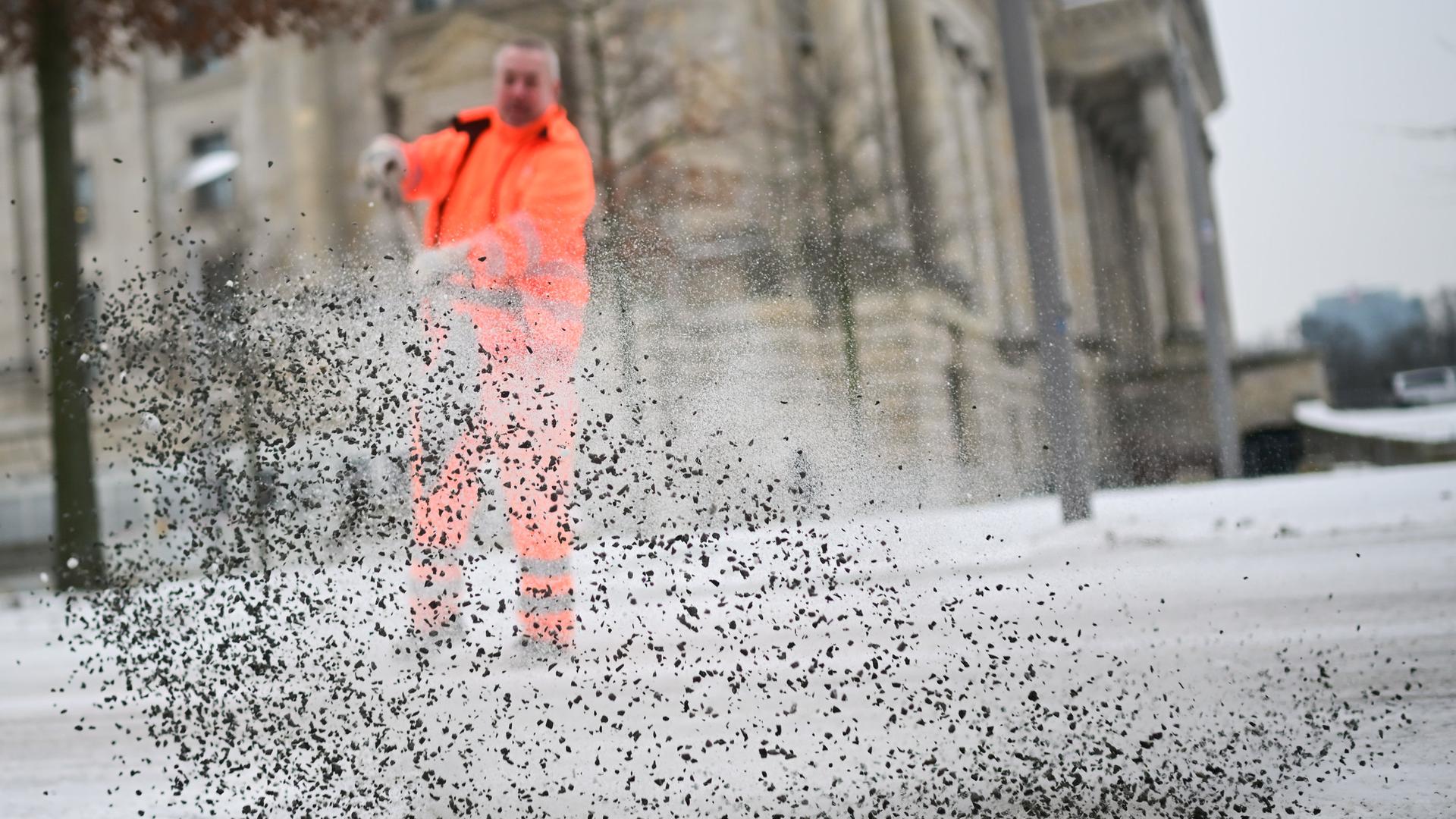 Ein Winterdienst-Mitarbeiter streut eine Mischung aus Salz und Splitt auf die zugeschneite Straße. | dpa-Bildfunk, Sebastian Gollnow